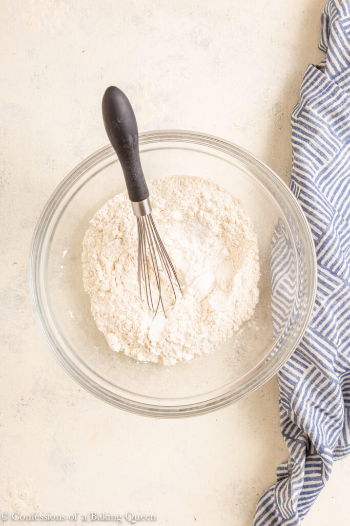 dry ingredients whisked together on a white surface with a blue linen