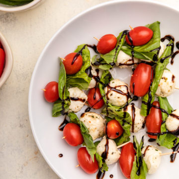 plate full of caprese skewers with balsamic glaze on top