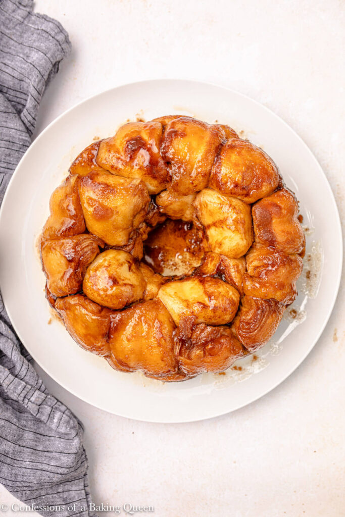 monkey bread just flipped out on a white serving platter on a light pink surface with a blue linen