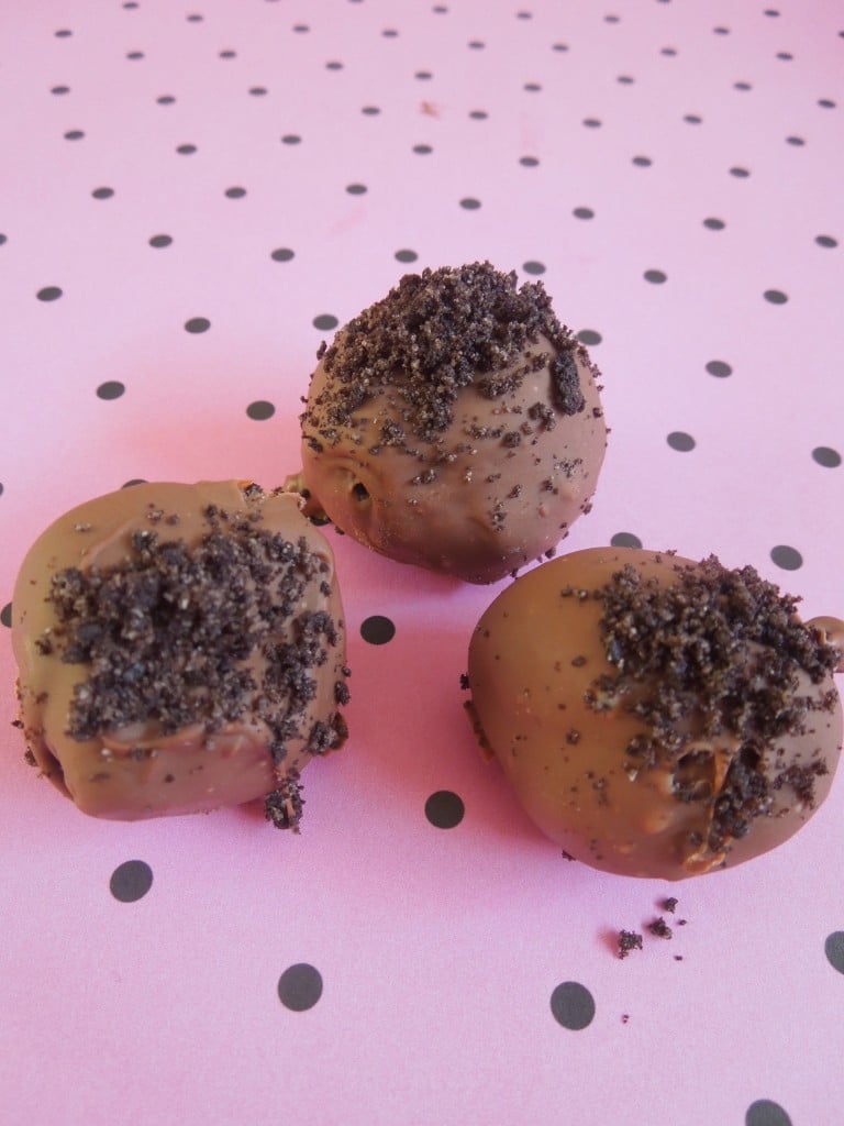 three oreo truffles on a pink and black polka dot background