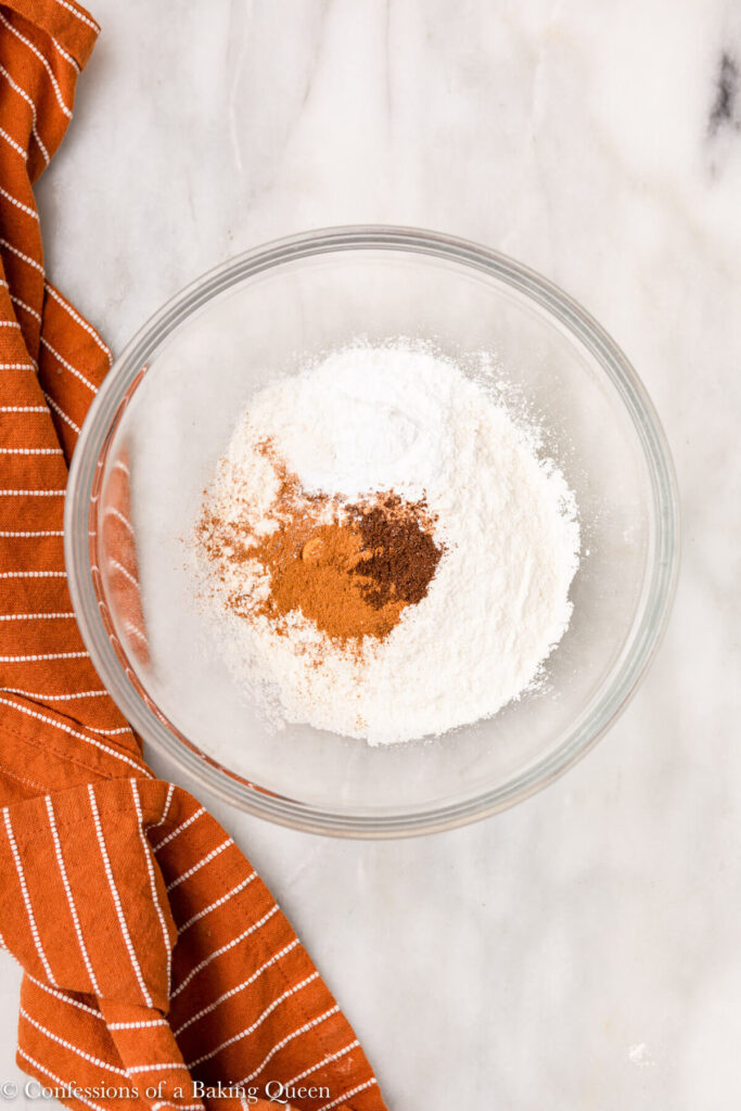 dry ingredients in a glass bowl on a white marble surface with an orange linen