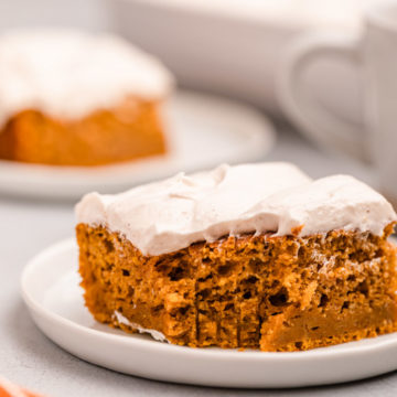 pumpkin bars with cream cheese frosting on white plates on a grey background