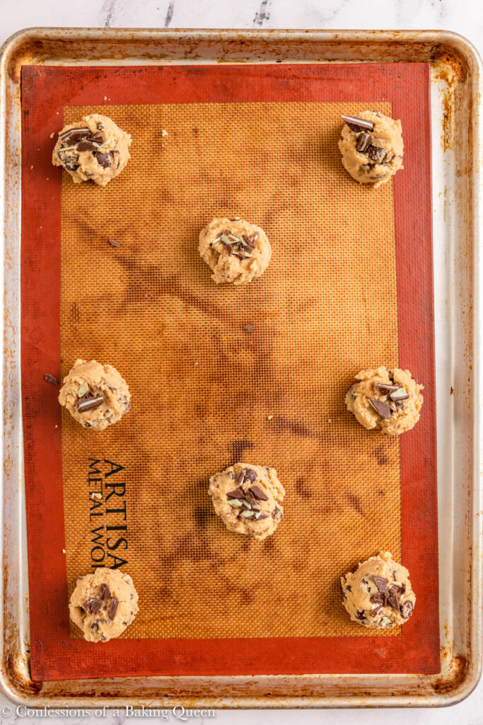 andes chocolate chip cookie dough balls on a silicone baking sheet before baking on a white marble surface