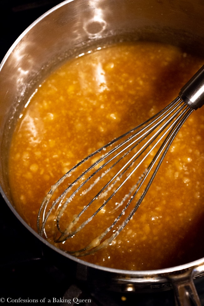 sugar turning to liquid and caramel in color in a silver heavy bottomed pan