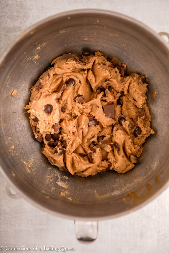 brown butter chocolate chip cookie dough in a metal mixing bowl on a light grey surface