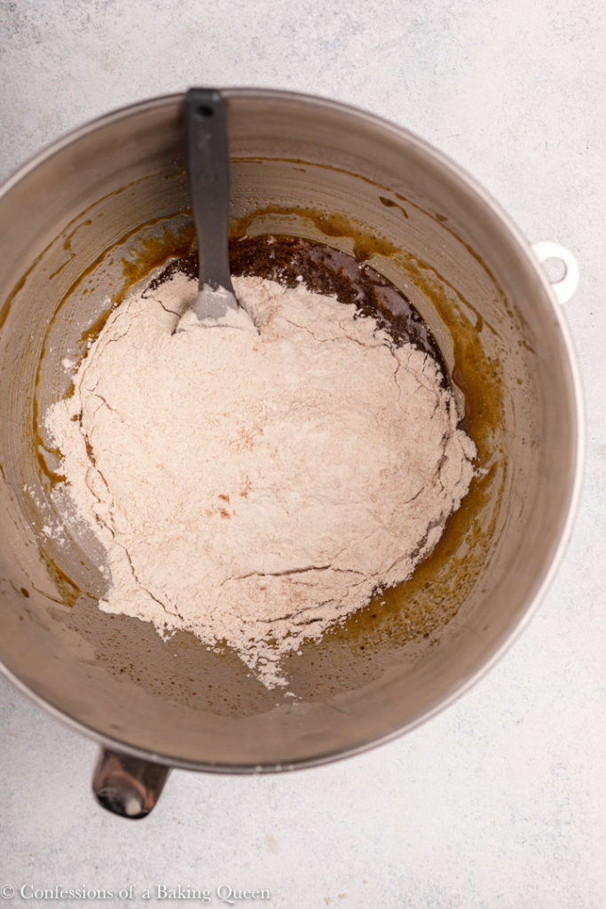 flour added to wet ingredients in a metal mixing bowl