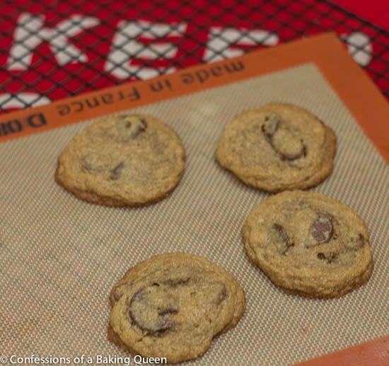 Oat Flour Chocolate Chip Cookies baked and cooling on a silpat liner on a wire rack on a red linen