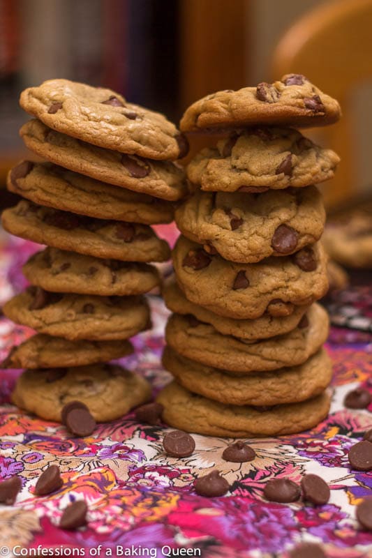 Perfect Chocolate Chip Cookies stacked high on a purple and pink tea towel