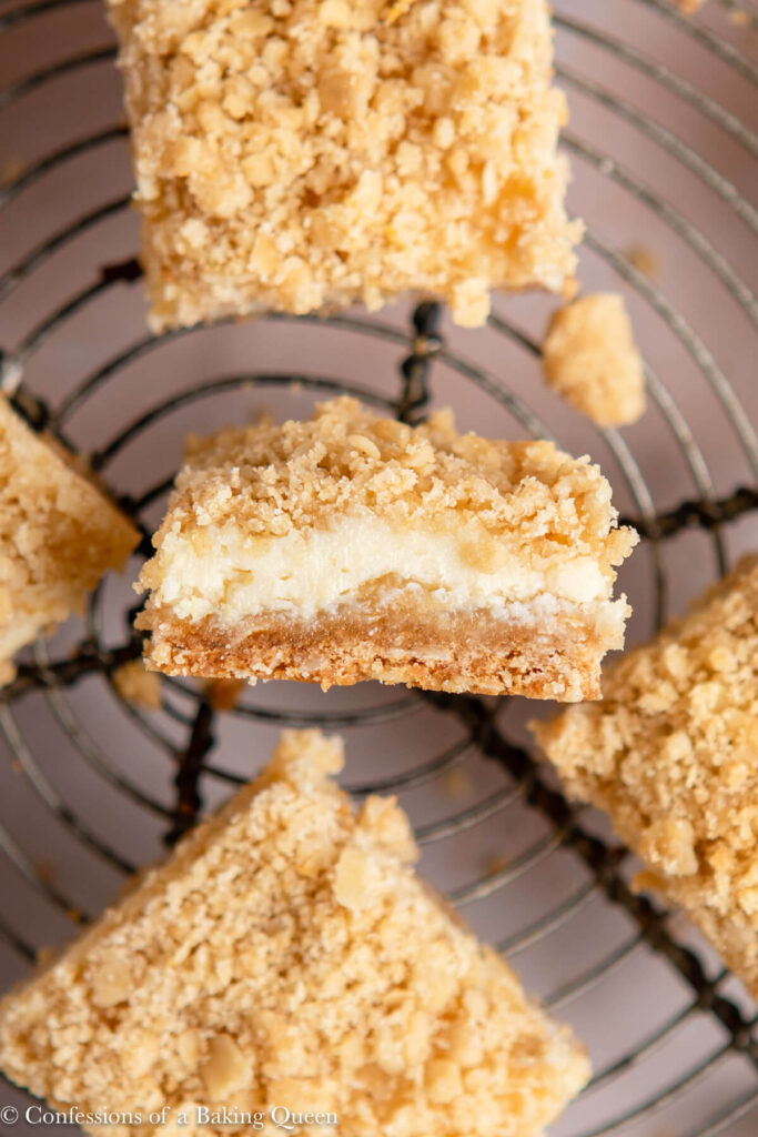 close up of lemon crumb bars on a wire rack on a light pink surface
