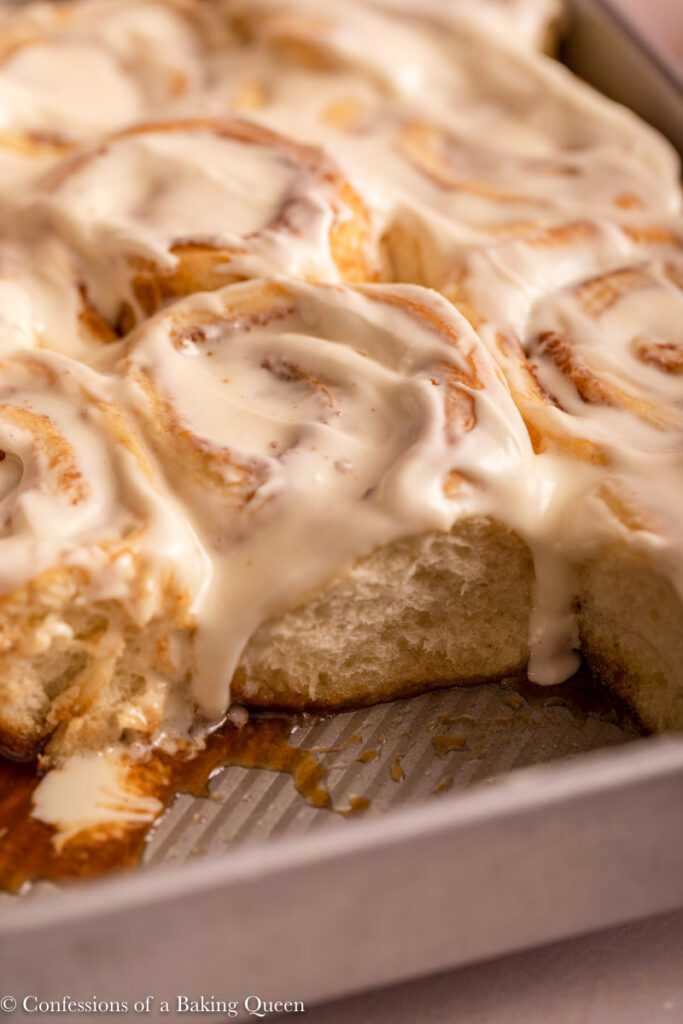 close up of cream cheese frosted cinnamon rolls in a pan