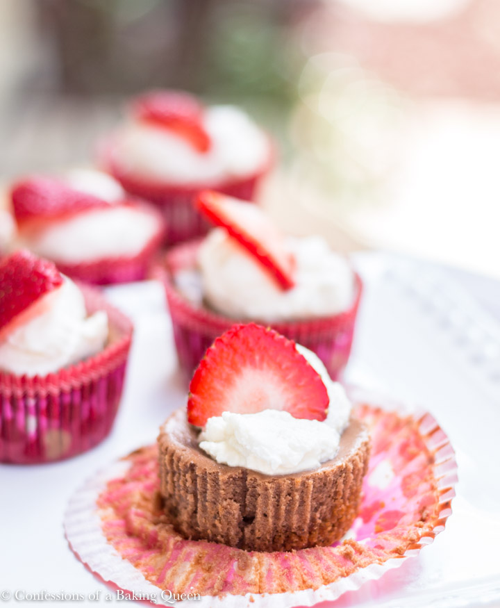 double chocolate cheesecake cups with whipped cream and strawberries on white plate