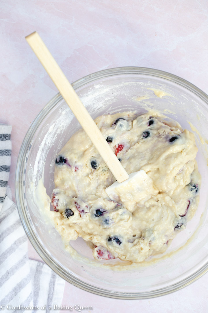 strawberry and blueberry muffin batter in a glass bowl with a white spatula