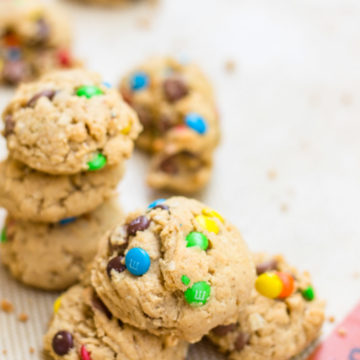 Brown Butter Oat & M&M Cookies baked and stacked on top of each other on a silpat lined baking sheet