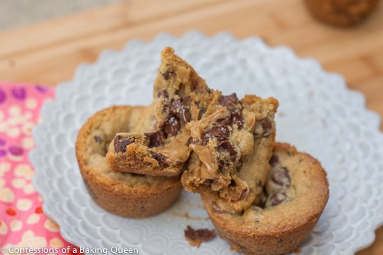 Biscoff Stuffed Chocolate Chip Cookie open on top of more cookie cups on a purple plate next to a pink linen on a wood board