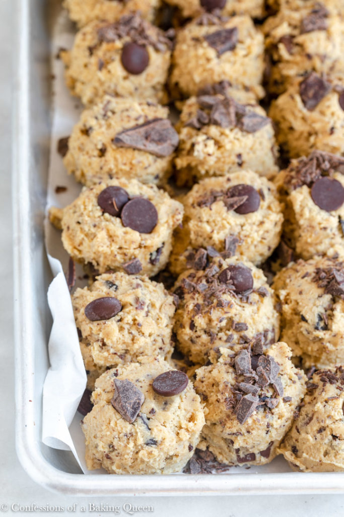 close up of peanut butter chocolate chip cookie dough balls on a parchment-lined baking sheet