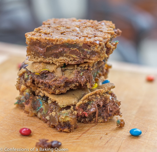 pretzel m&m blondies baked and stacked on a wood board showing off the pretzel crust