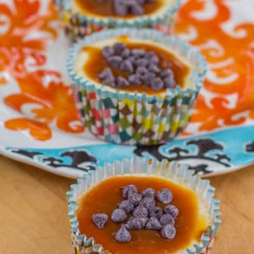 Rolo Cheesecake Cups lined up on a wood board and colorful plate