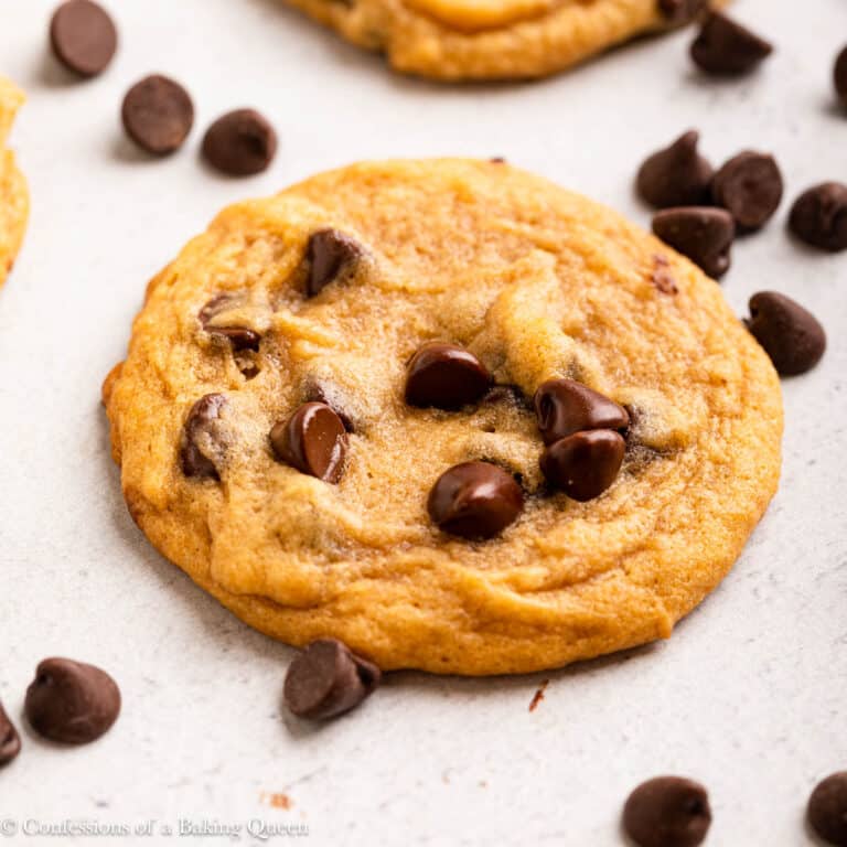 salted caramel chocolate chip cookies laid out on a grey surface with chocolate chips