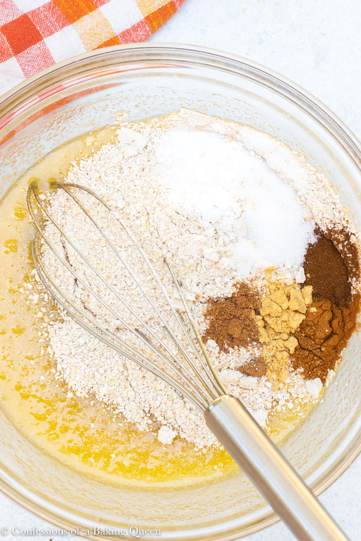 dry ingredients added to wet batter on a white background with an orange, yellow, and white linen