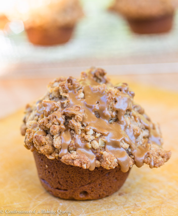 maple glazed pumpkin muffin on a wood board with more muffins in the background