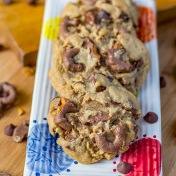 Chocolate Covered Pretzel Peanut Butter Cookies on a white plate with colorful dots on a wood board