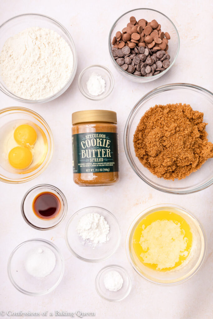 ingredients for cookie butter blondies in glass bowls on an light pink surface