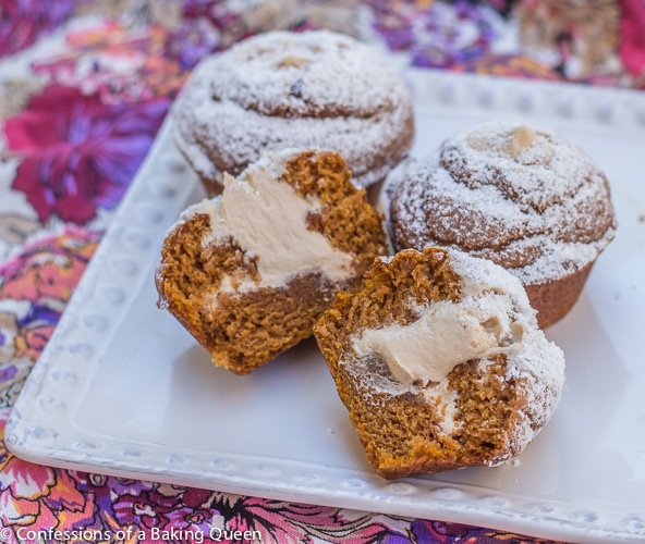 Maple Cream Filled Pumpkin Muffins cut open served on a white plate on a pink and purple floral linen