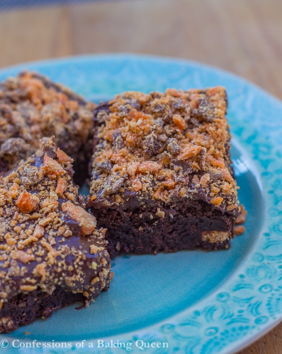 butterfinger brownies three pieces on a blue plate on a wood surface