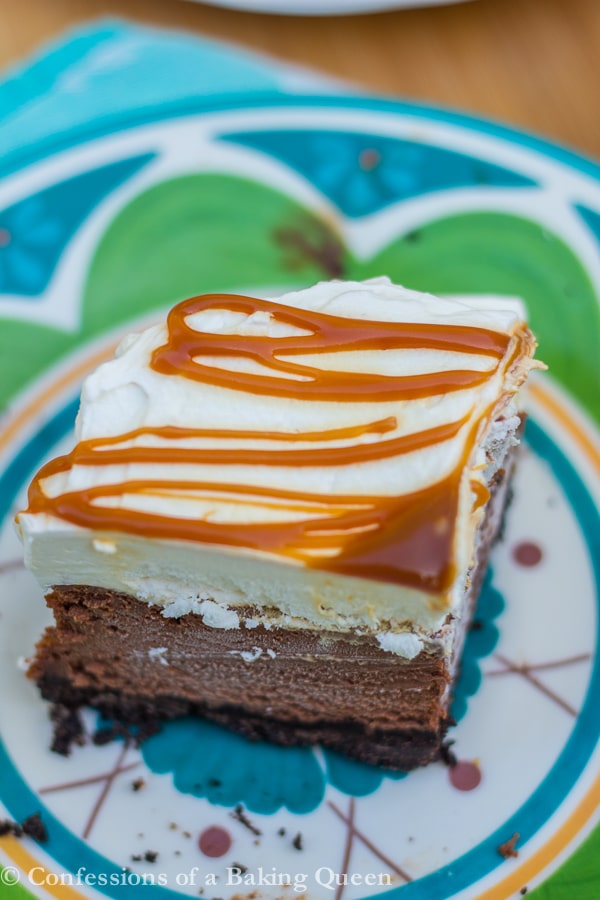 Salted Caramel Chocolate Cheesecake Bars up close on a blue and green plate on a wood board
