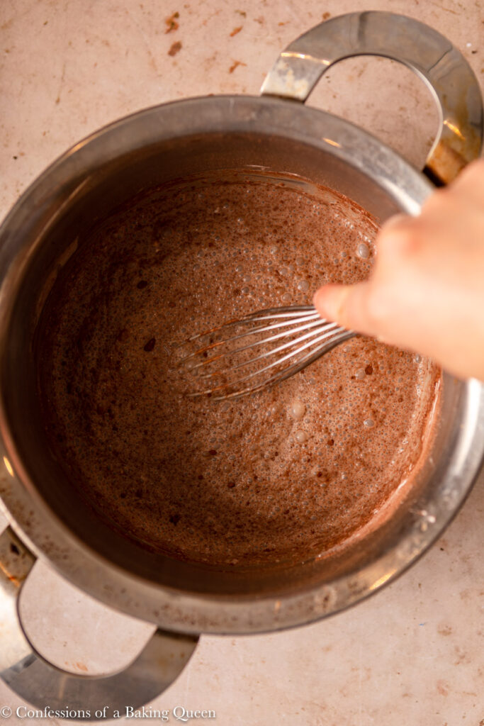 hand whisking chocolate filling ingredients together on a light brown surface