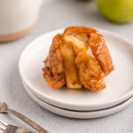 apple monkey bread muffin on a white plate next to a cup of coffee