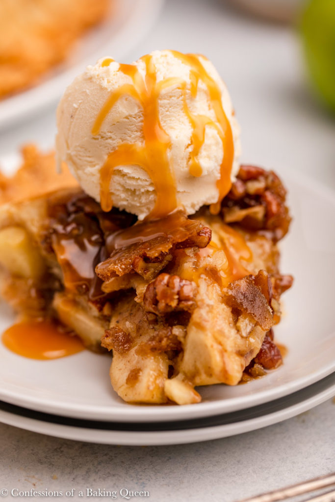 slice of salted caramel upside down apple pie with ice cream on a white plate 