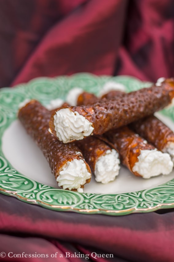 Brandy Snaps up close on white and green plate on top of a dark red linen
