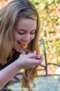 Blonde girl outside taking a bite of Rosa Lasagna 