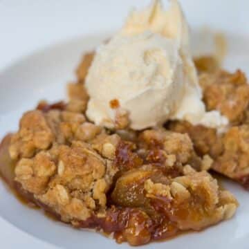 salted caramel apple crisp served in a white dish with ice cream on top