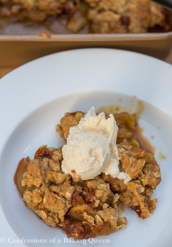 Caramel Apple Crisp in a white bowl with an ice cream scoop on top 