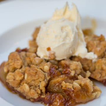 salted caramel apple crisp served in a white dish with ice cream on top
