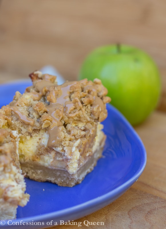Maple Apple Cheesecake Bars on a blue plate with a green apple in the background on a wood background