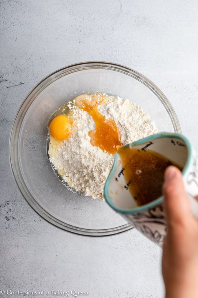 brown butter poured into cake mix and egg in a glass bowl on a grey surface