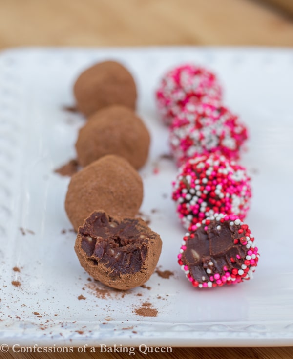 kahlua toffee truffles rolled in cocoa powder and sprinkles on a white plate on a wood board