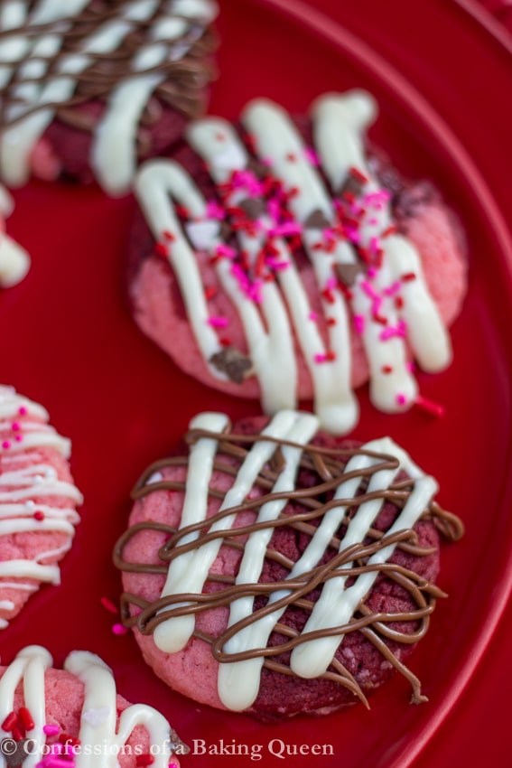 Strawberry Red Velvet Swirl Cookies with white and milk chocolate drizzle on red plate