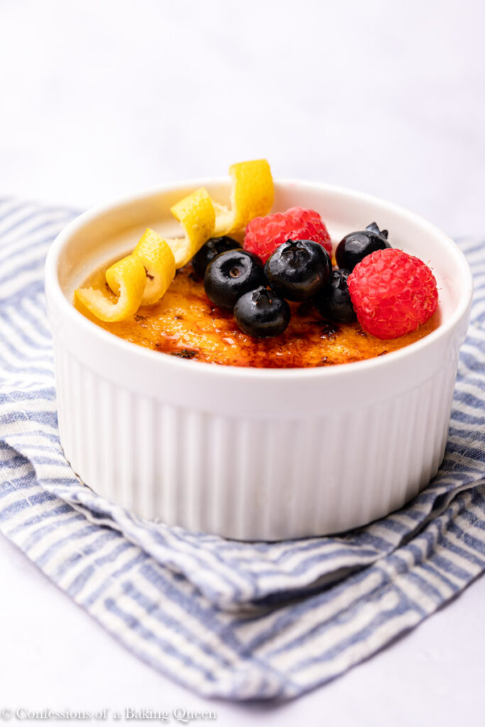 lemon creme brulee with berries served on a blue linen on a white surface with a blue linen
