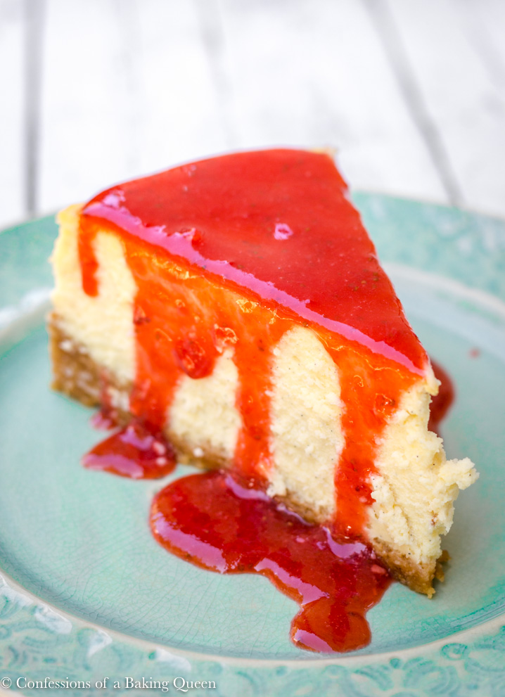 vanilla bean cheesecake slice with strawberry sauce on a turquoise plate