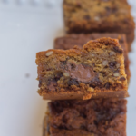 salted caramel pecan chocolate chip blondies stacked on top of each other on a white plate