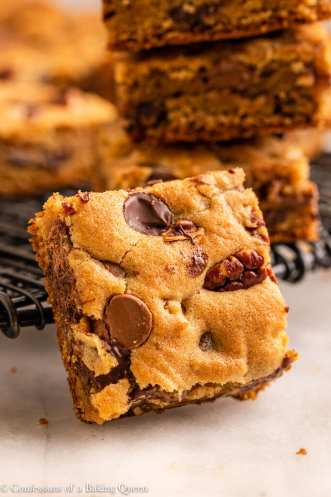close up of a pecan chocolate chip blondie against a wire rack