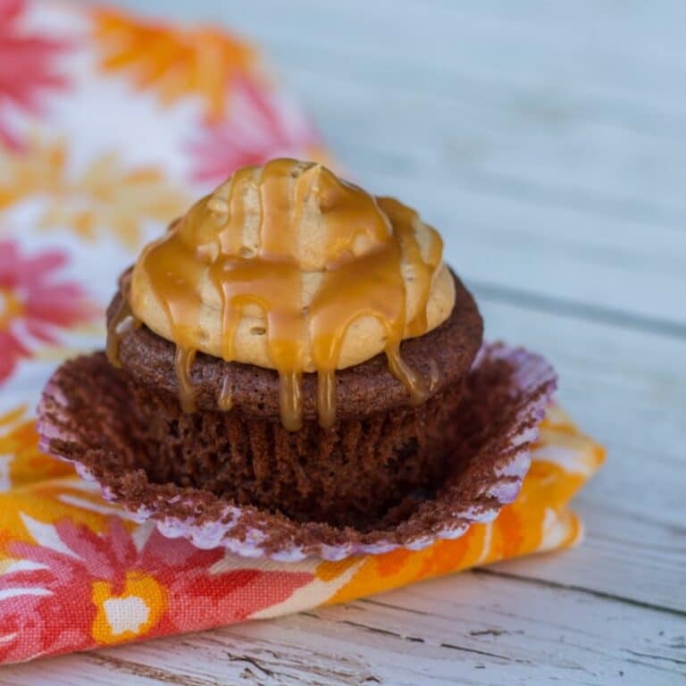 Coffee Caramel Chocolate Cupcake unwrapped and sitting on a flowery tea towel on a white wood background