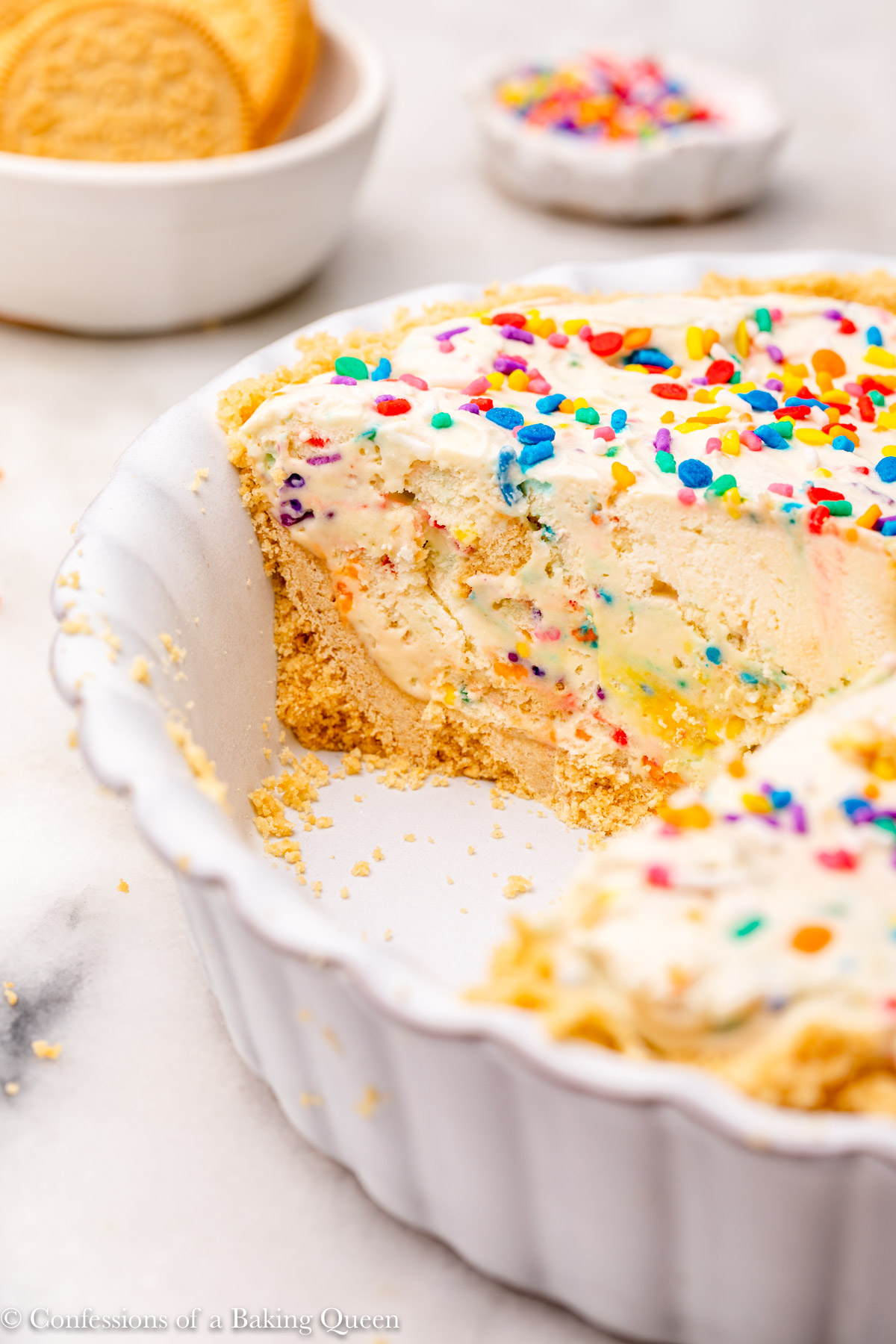golden oreo cake batter pie cut open in a light purple pie dish on a white marble surface