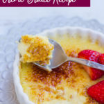 the best vanilla bean creme brulee in a white ramekin with a silver spoon breaking the sugar top