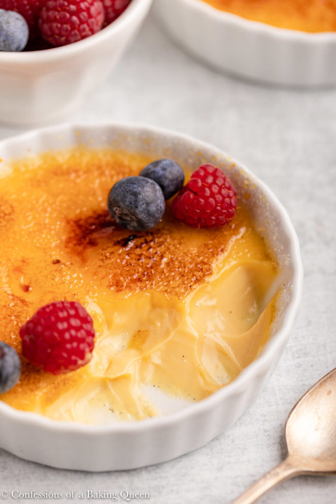 salted caramel creme brulee with a few bites taken out next to a bowl of berries 