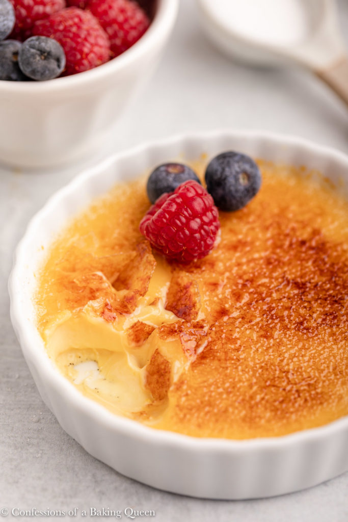 salted caramel creme brulee with a few bites taken out next to a bowl of berries